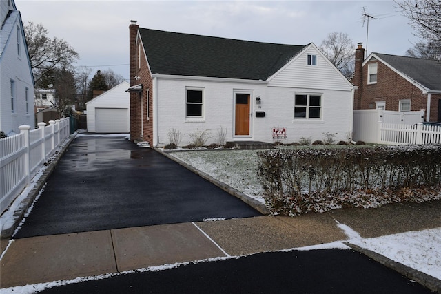 view of front of property featuring a chimney, fence, an outdoor structure, and brick siding