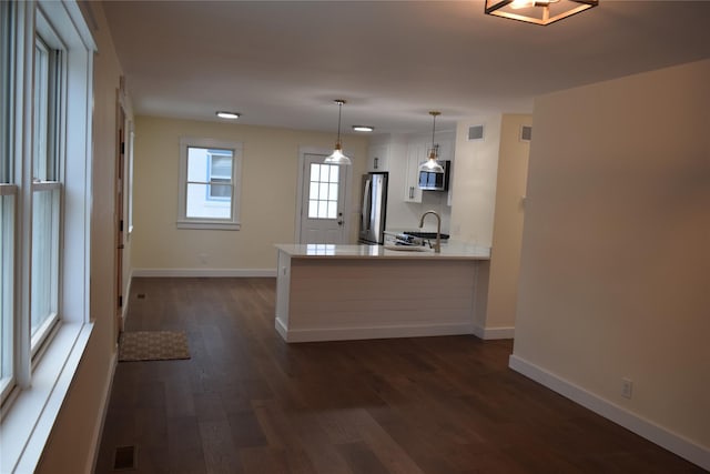 kitchen with visible vents, dark wood-style floors, a peninsula, stainless steel appliances, and a sink