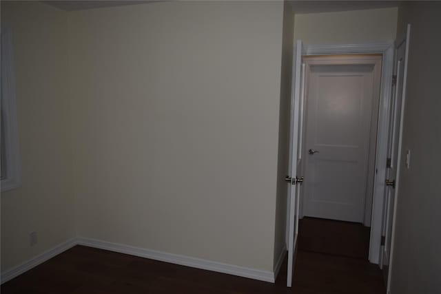 unfurnished room with dark wood-style flooring and baseboards