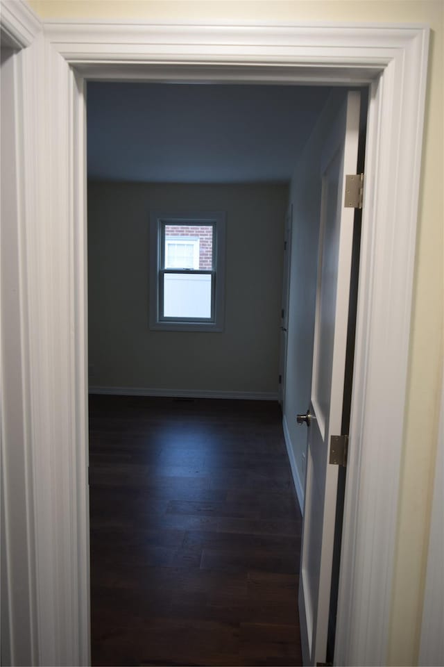 hallway with dark wood-type flooring and baseboards