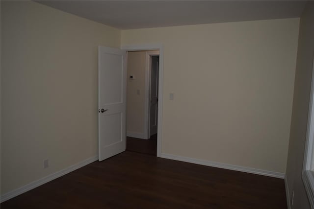 spare room featuring dark wood-style floors and baseboards