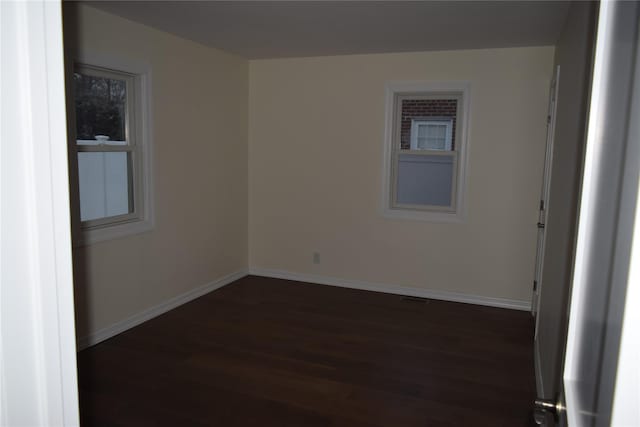 spare room featuring baseboards and dark wood finished floors