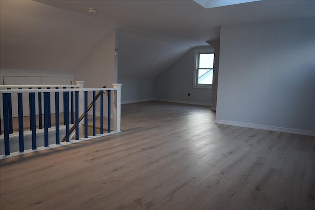 bonus room featuring vaulted ceiling with skylight, baseboards, and wood finished floors