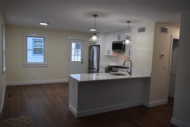 kitchen featuring a peninsula, visible vents, stainless steel appliances, and dark wood-type flooring