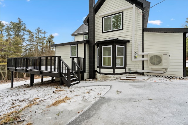 snow covered house featuring ac unit and a deck