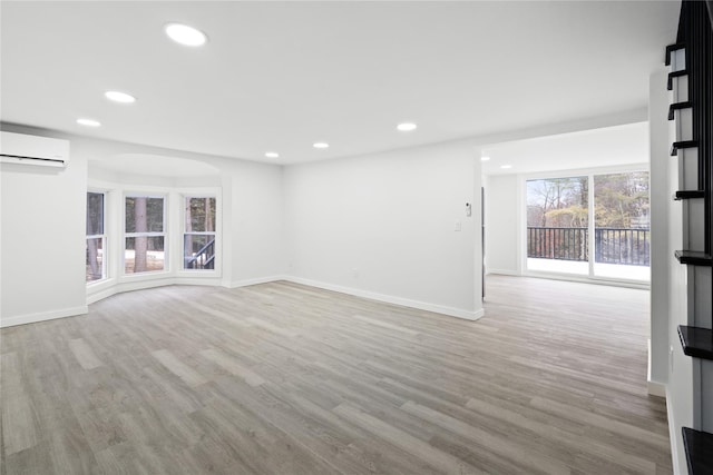 spare room with a wall mounted air conditioner and light hardwood / wood-style floors