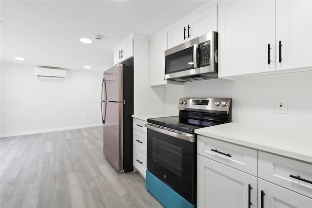 kitchen featuring white cabinetry, appliances with stainless steel finishes, a wall unit AC, and light wood-type flooring