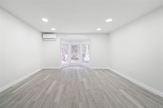 unfurnished room with an AC wall unit and light hardwood / wood-style floors