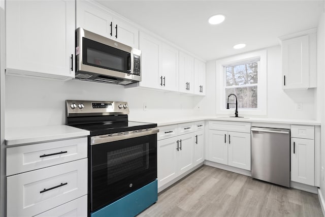 kitchen with white cabinetry, sink, light hardwood / wood-style flooring, and appliances with stainless steel finishes