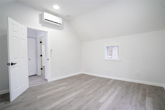 additional living space with lofted ceiling, a wall mounted air conditioner, and light hardwood / wood-style floors