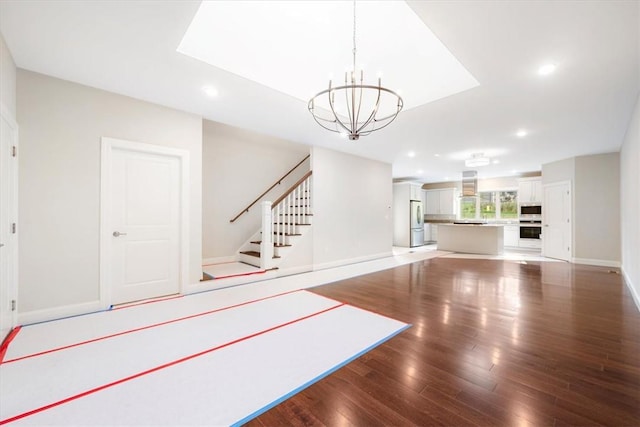 unfurnished living room with a chandelier and hardwood / wood-style floors