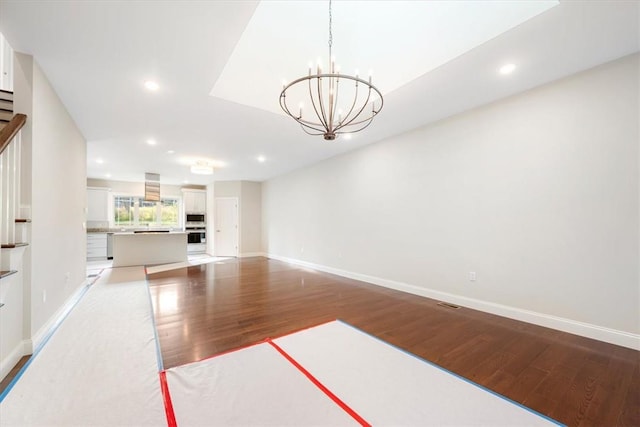 unfurnished living room with a chandelier and hardwood / wood-style flooring