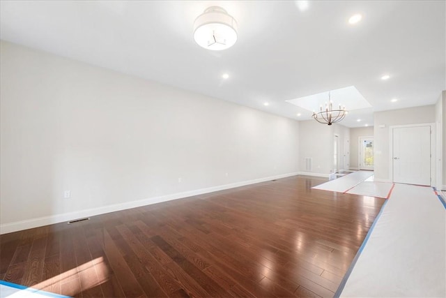 unfurnished living room with a chandelier and dark wood-type flooring