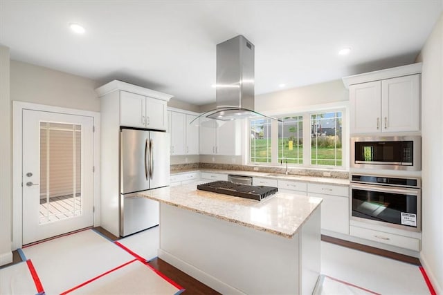 kitchen featuring island exhaust hood, a center island, stainless steel appliances, and white cabinets