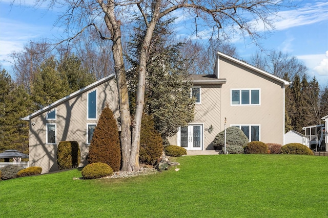 back of property with french doors, a yard, and stucco siding