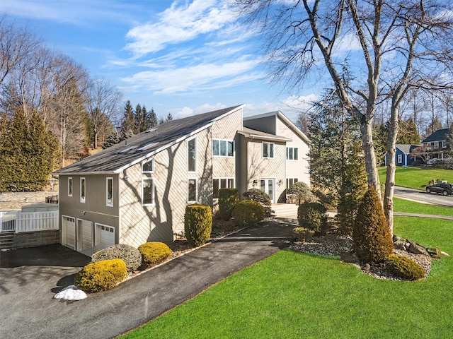 view of side of property featuring a garage, a yard, and aphalt driveway