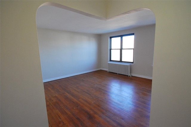 spare room with dark hardwood / wood-style flooring and radiator heating unit