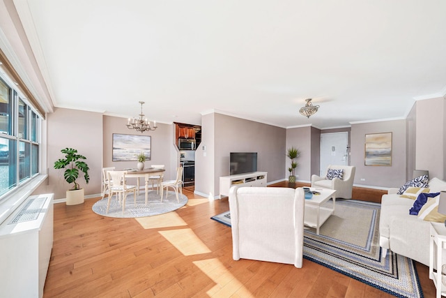 living room featuring light hardwood / wood-style flooring, ornamental molding, and an inviting chandelier