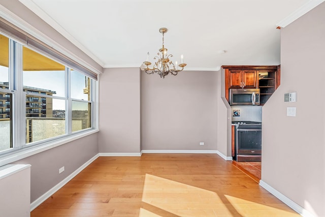 unfurnished dining area with an inviting chandelier, crown molding, and light hardwood / wood-style flooring