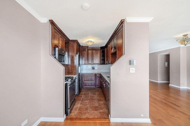 kitchen featuring decorative backsplash, dark brown cabinetry, stainless steel appliances, crown molding, and dark hardwood / wood-style floors