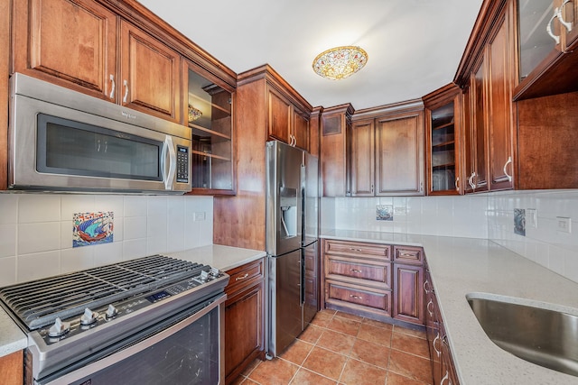 kitchen with decorative backsplash, light tile patterned floors, stainless steel appliances, and light stone counters