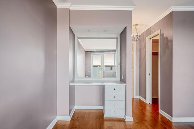 hall with wood-type flooring, an inviting chandelier, and crown molding