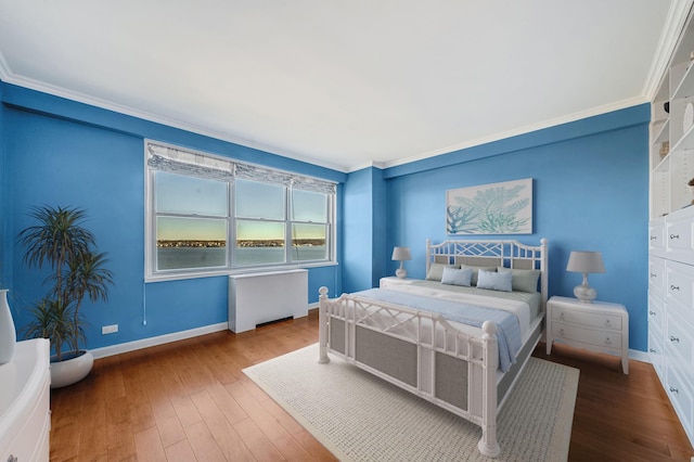 bedroom featuring radiator heating unit, hardwood / wood-style flooring, and crown molding