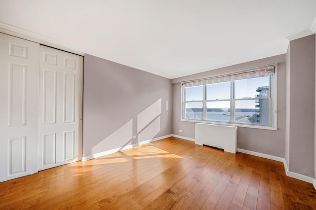 spare room with radiator heating unit, hardwood / wood-style flooring, and crown molding