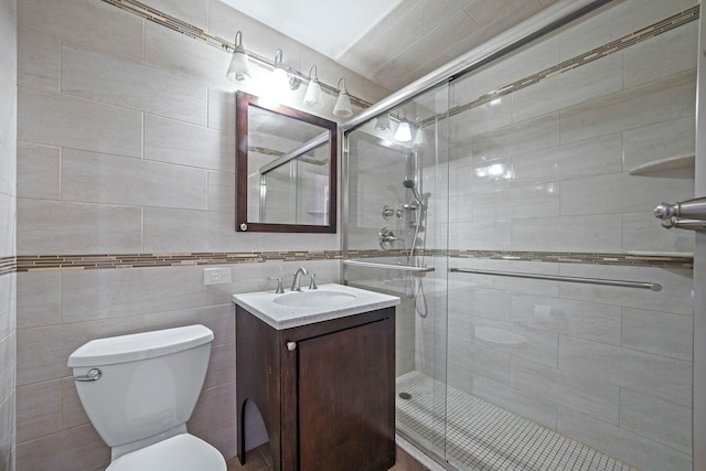 bathroom featuring vanity, toilet, walk in shower, and tile walls