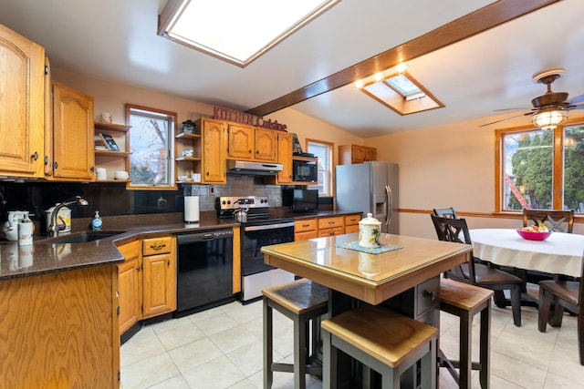 kitchen featuring black appliances, lofted ceiling with skylight, sink, and tasteful backsplash