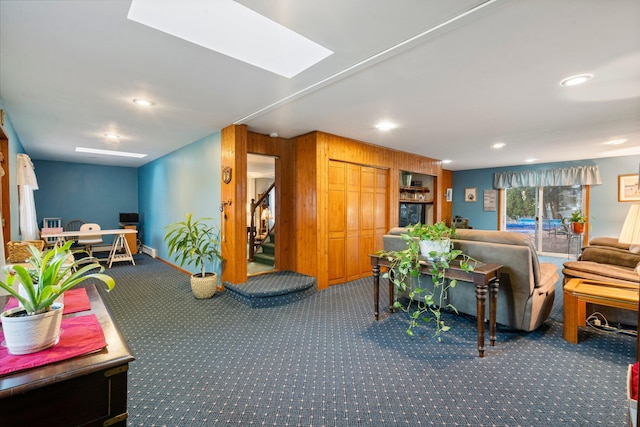 interior space with carpet flooring, a skylight, and wooden walls