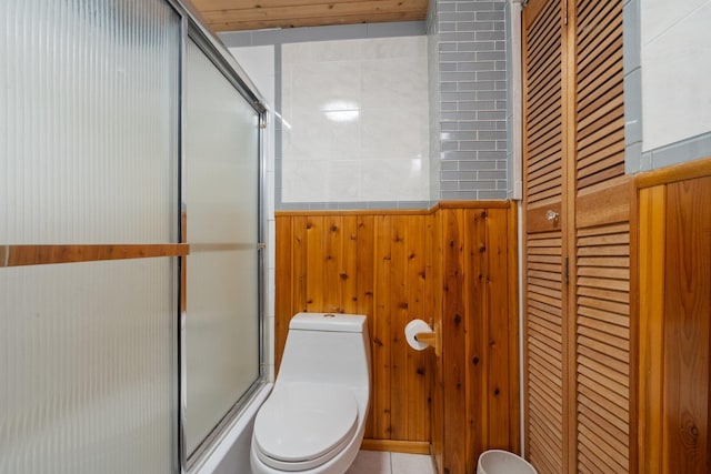 bathroom featuring toilet, a shower with shower door, and wooden walls