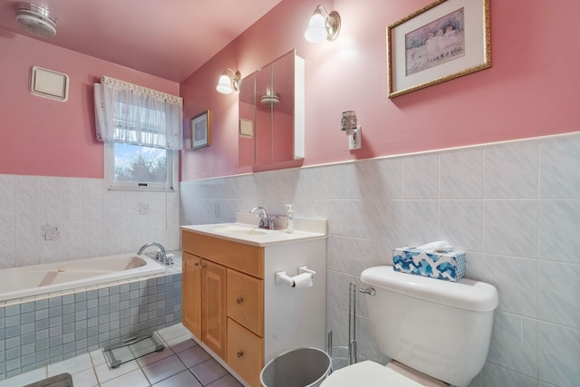 bathroom featuring vanity, tile patterned flooring, toilet, tile walls, and tiled bath