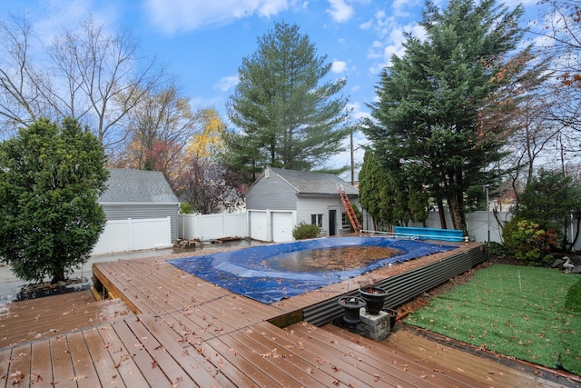 view of pool with a garage, an outbuilding, and a wooden deck