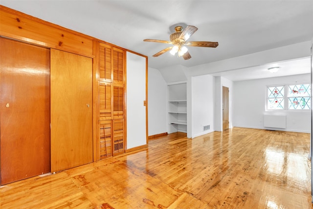 additional living space featuring built in shelves, ceiling fan, light hardwood / wood-style flooring, and vaulted ceiling