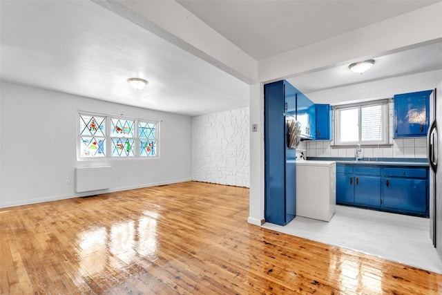 kitchen featuring backsplash, light hardwood / wood-style floors, and blue cabinetry