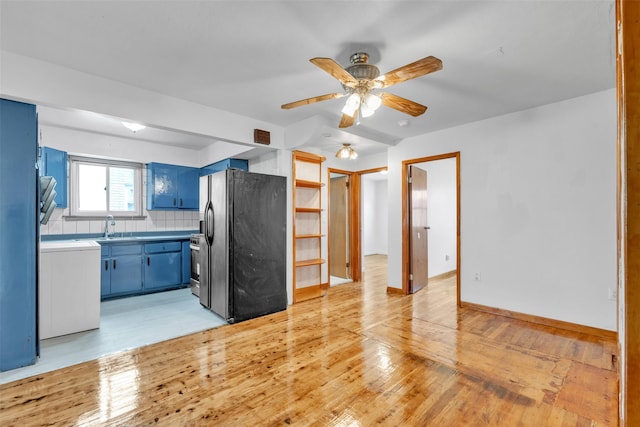 kitchen with tasteful backsplash, black refrigerator with ice dispenser, ceiling fan, blue cabinetry, and light hardwood / wood-style flooring