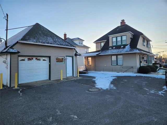 view of front of property featuring a garage, a chimney, and an outbuilding