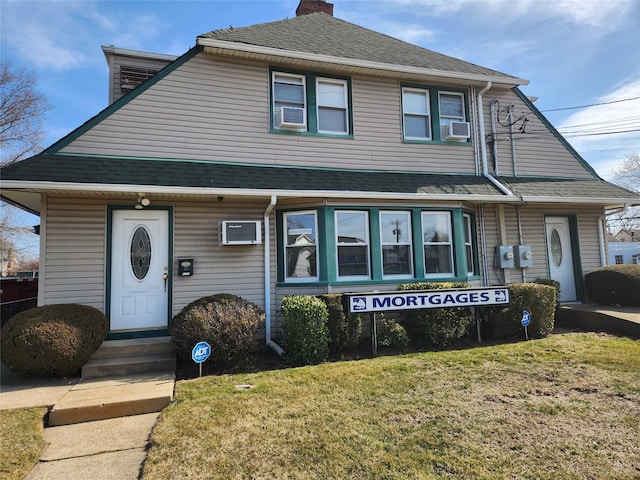 view of front facade with a front lawn, roof with shingles, and a chimney