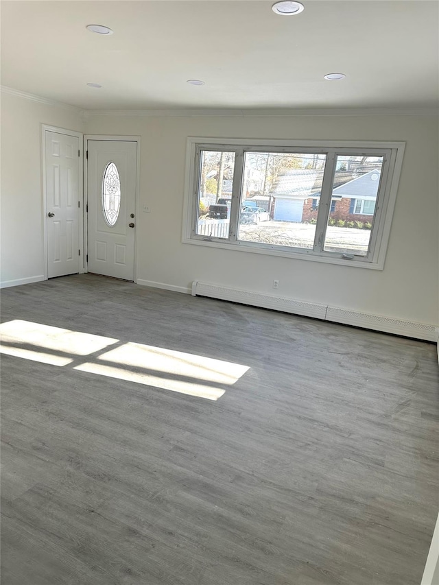 foyer with ornamental molding, light wood-type flooring, and a baseboard heating unit