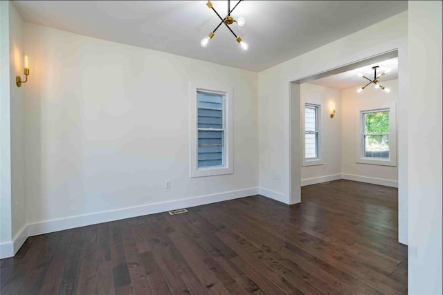 unfurnished room featuring a notable chandelier and dark hardwood / wood-style flooring