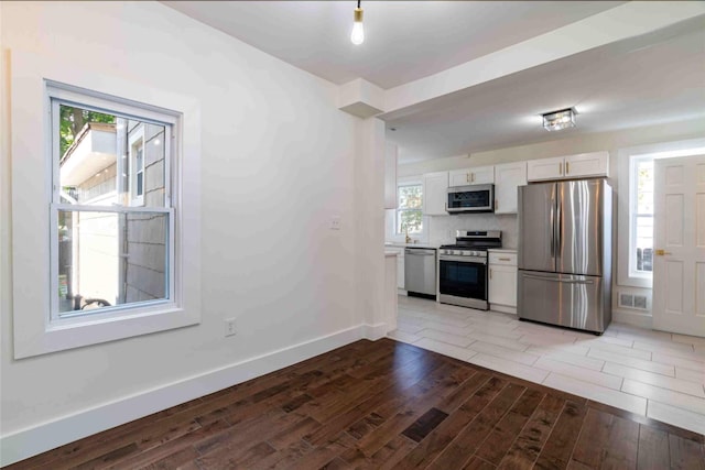 kitchen with stainless steel appliances, white cabinets, and tasteful backsplash