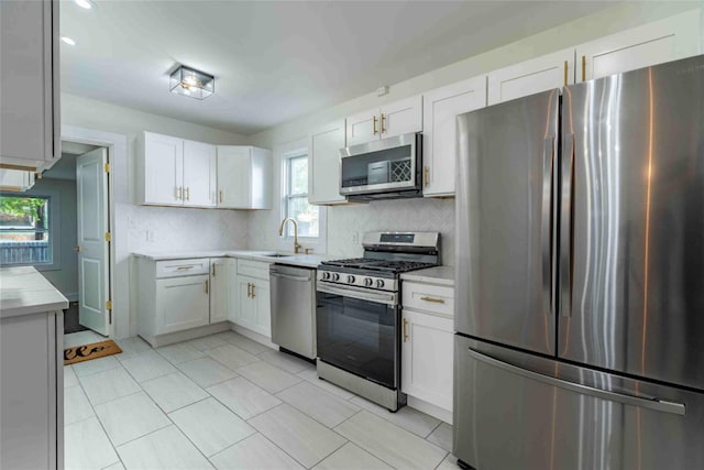 kitchen featuring sink, decorative backsplash, white cabinetry, and appliances with stainless steel finishes