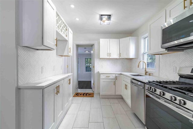 kitchen with stainless steel appliances, white cabinets, and sink