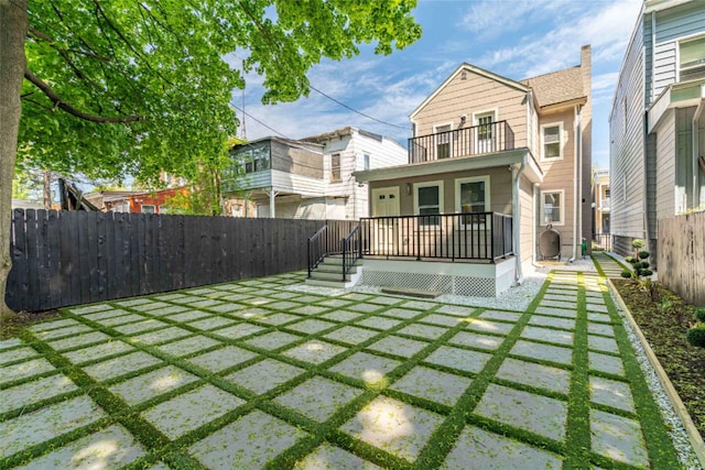 rear view of property featuring a balcony and a lawn