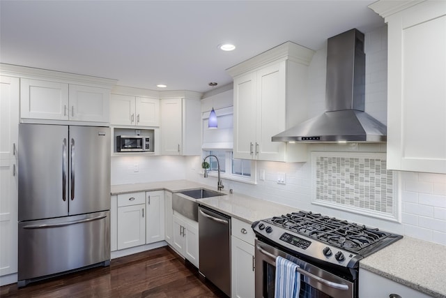 kitchen with white cabinets, wall chimney range hood, sink, hanging light fixtures, and stainless steel appliances