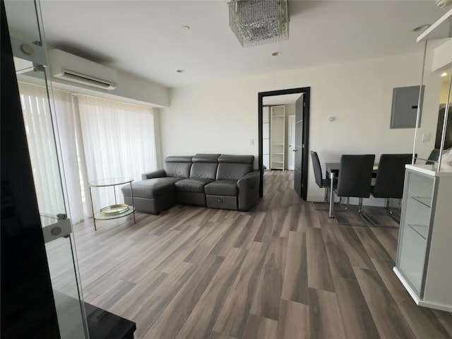 living room with a wall unit AC, electric panel, dark hardwood / wood-style flooring, and a chandelier