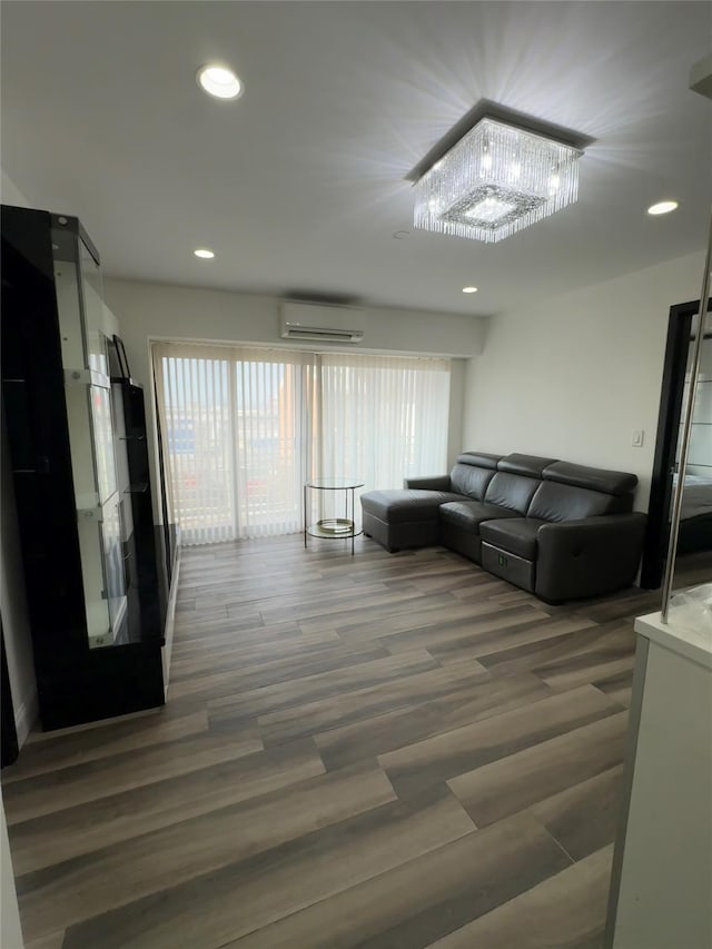 living room with a wealth of natural light, dark hardwood / wood-style flooring, a wall unit AC, and a chandelier