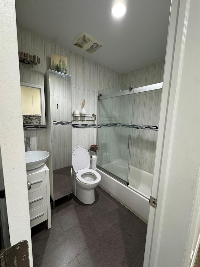 full bathroom with vanity, bath / shower combo with glass door, and toilet