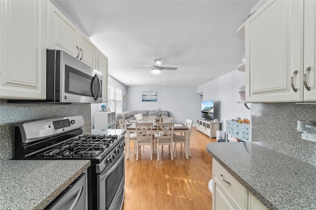 kitchen featuring light hardwood / wood-style flooring, ceiling fan, appliances with stainless steel finishes, white cabinetry, and decorative backsplash